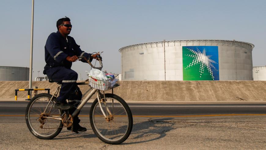 An employee rides a bicycle next to oil tanks at Saudi Aramco oil facility in Abqaiq, Saudi Arabia October 12, 2019. REUTERS/Maxim Shemetov - RC23VF99O3SV