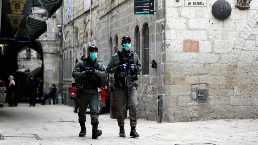 Israeli police wearing masks walk near a bronze sculpture by Italian artist Alessandro Mutto at one of the Stations of the Cross along the Via Dolorosa, amid the coronavirus disease (COVID-19) outbreak in Jerusalem's Old City April 2, 2020. Picture taken April 2, 2020. REUTERS/Ammar Awad - RC2WYF955Z7O