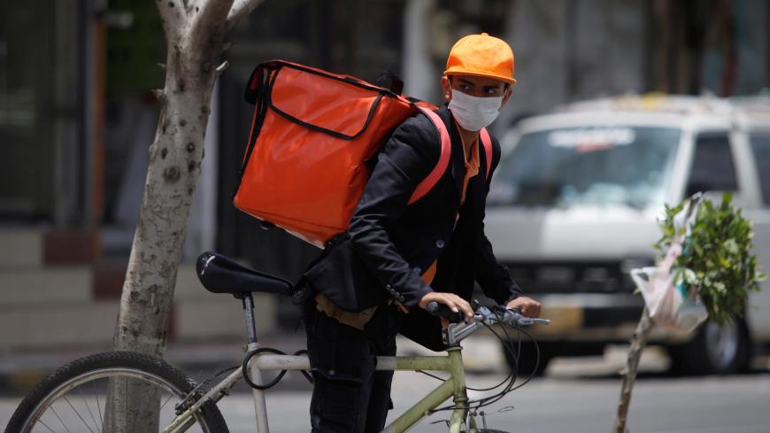 A delivery man wearing a protective face mask rides his bicycle, amid fear of coronavirus disease (COVID-19), in Sanaa, Yemen April 10, 2020. REUTERS/Mohamed al-Sayaghi - RC2Q1G92ES6L