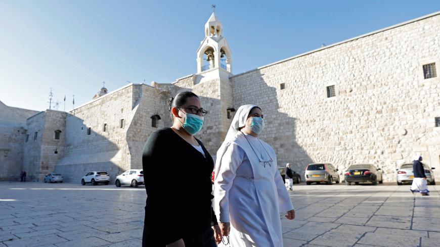 Women walk outside the Church of the Nativity as it reopens after Palestinians ease the restrictions of the coronavirus disease (COVID-19), in Bethlehem in the Israeli-occupied West Bank May 26, 2020. REUTERS/Mussa Qawasma - RC26WG93LYX0
