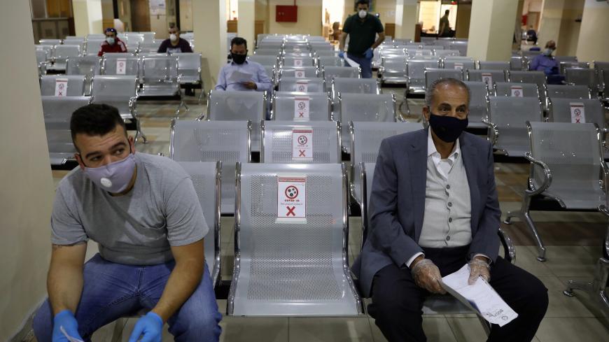 People  wearing protective face masks wait to complete their transactions in the Civil Status Department after Jordan's public sector employees returned gradually to work, two months after they were ordered to stay home as part of a tight lockdown to stem the spread of the coronavirus disease (COVID-19), in Amman, Jordan May 26, 2020. REUTERS/Muhammad Hamed - RC2CWG9G4C2S