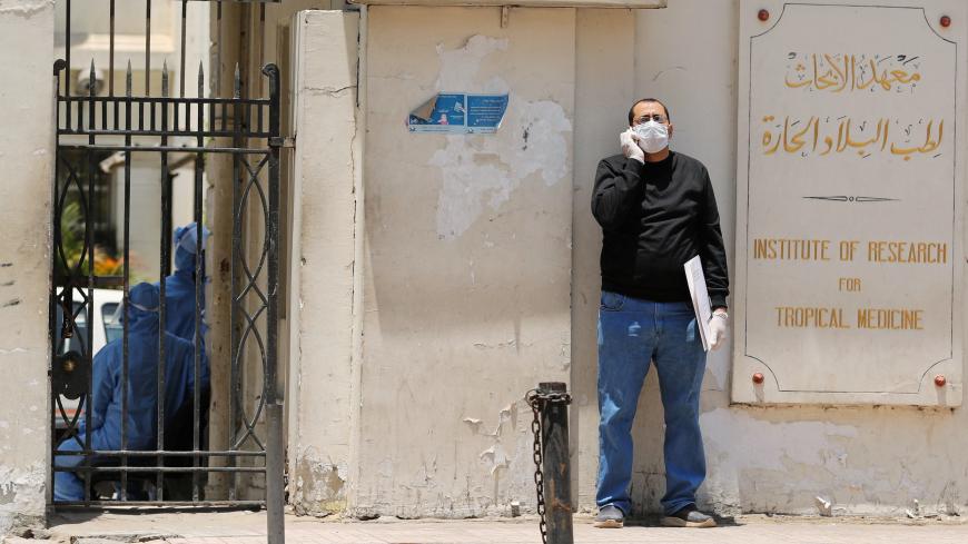 A man wearing protective face mask and gloves stands outside the Institute of Research for Tropical Medicine amid concerns about the spread of the coronavirus disease (COVID-19), in Cairo, in Egypt May 26, 2020. Picture taken May 26, 2020. REUTERS/Staff - RC2KXG912PCZ