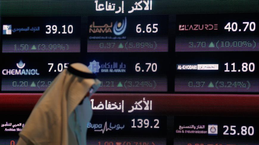 An investor walks past a screen displaying stock information at the Saudi Stock Exchange (Tadawul) in Riyadh, Saudi Arabia June 29, 2016. REUTERS/Faisal Al Nasser  - S1AETMRJVXAC