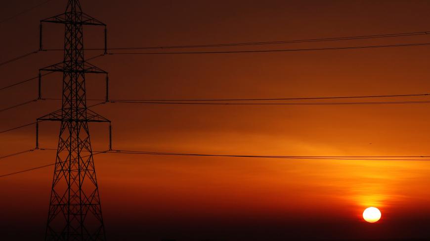 The sun is seen behind high-voltage power lines and electricity pylons at a highway northeast of Cairo, Egypt, March 13, 2019. REUTERS/Amr Abdallah Dalsh - RC19CACD69D0