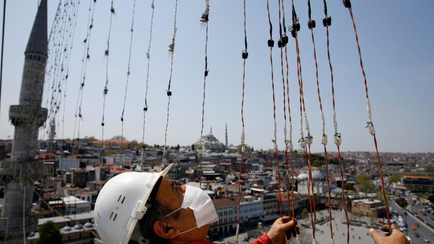 Mahya master Ramazan Kizilkaya takes part in the installation of the mahya at the top of one of the minarets of Yeni New mosque, as the outbreak of the coronavirus disease (COVID-19) continues in Istanbul, Turkey, April 27, 2020. Picture taken April 27, 2020. REUTERS/Umit Bektas - RC2LDG9HE58T