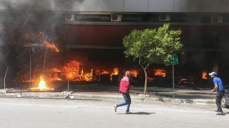 Demonstrators are seen near a bank on fire during unrest, as an economic crisis brings demonstrations back onto the streets in Tripoli, Lebanon April 28, 2020. REUTERS/Omar Ibrahim - RC2ODG9O5VDN