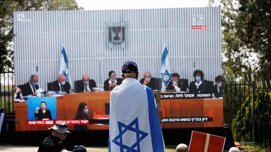 Israelis protest in front of a placard with the photo of the High Court judges outside the Knesset, the Israeli parliament, against Prime minister Benjamin Netanyahu, who is charged with corruption, serving as prime minister of Israel's new unity government amid the coronavirus disease (COVID-19) outbreak in Jerusalem May 3, 2020 REUTERS/ Ronen Zvulun - RC2VGG9KUA09