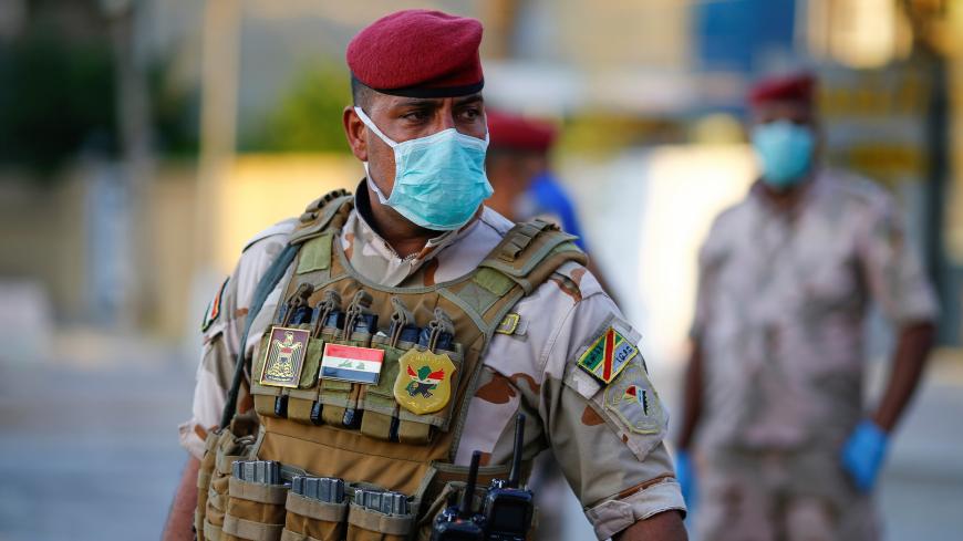An Iraqi soldier wears a protective face mask as he stands guard at a check point, enforcing a curfew imposed to prevent the spread of the coronavirus disease (COVID-19), during the holy fasting month of Ramadan, in Baghdad, Iraq May 3, 2020.REUTERS/Thaier Al-Sudani - RC26HG9KD5MD
