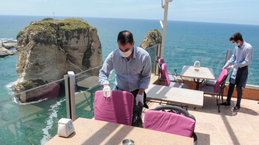 Waiters fix chairs at a restaurant overlooking the Pigeons Rock, as Lebanon begins to ease nationwide lockdown due to spread of the coronavirus disease (COVID-19) in Beirut, Lebanon May 4, 2020. REUTERS/Aziz Taher - RC2PHG9CXB7K