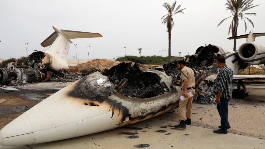 A policeman and a man inspect a passenger plane damaged by shelling at Tripoli's Mitiga airport in Tripoli, Libya May 10, 2020. REUTERS/Ismail Zitouny - RC2MLG9IHJ7J