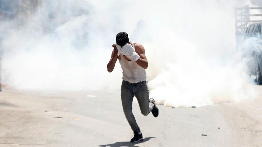 A Palestinian runs away from tear gas fired by Israeli forces during a raid after an Israeli soldier was killed by a rock, in Yabad near Jenin in the Israeli-occupied West Bank May 12, 2020. REUTERS/Mohamad Torokman - RC2YMG9FT10W