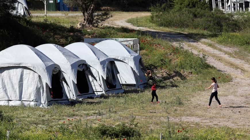 Two girls play next to tents at a temporary camp for newly arrived refugees and migrants, where cases of  coronavirus disease (COVID-19) were detected, on the island of Lesbos, Greece, May 13, 2020. REUTERS/Elias Marcou - RC2KNG9YQJIS