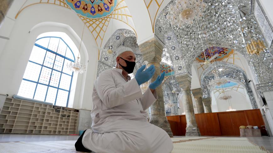 A muezzin of the shrine of Sheikh Abdul Qadir Jeelani prays alone since all places of worship remain closed as part of the preventive measures against the spread of the coronavirus disease (COVID-19) during the holy fasting month of Ramadan in Baghdad, Iraq May 13, 2020. REUTERS/Thaier al-Sudani - RC2ONG91TTPX
