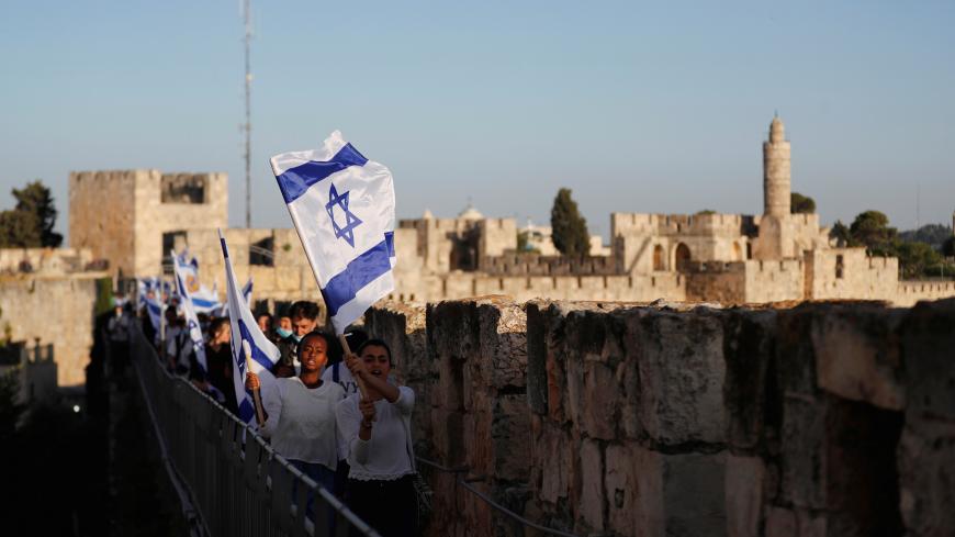 Israelis hold national flags and walk on the walls surrounding Jerusalem's Old City while celebrating "Jerusalem Day" as coronavirus disease (COVID-19) prevention restrictions ease May 21, 2020. REUTERS/Ronen Zvulun - RC24TG9W90G1