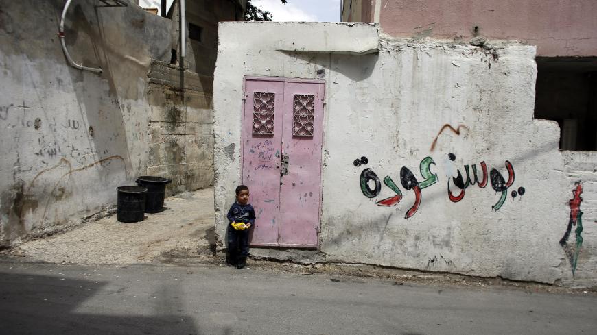 A Palestinian boy leans against the entrance to his house in Qalandiya Refugee Camp near the West Bank city of Ramallah, ahead of Nakba Day May 13, 2013. Palestinians will mark "Nakba" (Catastrophe) on May 15 to commemorate the expulsion or fleeing of some 700, 000 Palestinians from their homes in the war that led to the founding of Israel in 1948. The graffiti reads "Yousef Oude", a Palestinian prisoner held in an Israeli jail. REUTERS/Ammar Awad (WEST BANK - Tags: POLITICS CIVIL UNREST) - GM1E95E03ZE01