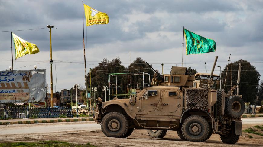 A patrol of US military vehicles is seen near the flying yellow flags of the Syrian Democratic Forces (SDF) and green flags of its constituent Women's Protection Forces (YPJ) in the town of Tal Tamr in the northeastern Syrian Hasakeh province along the border with Turkey on February 8, 2020. (Photo by Delil SOULEIMAN / AFP) (Photo by DELIL SOULEIMAN/AFP via Getty Images)