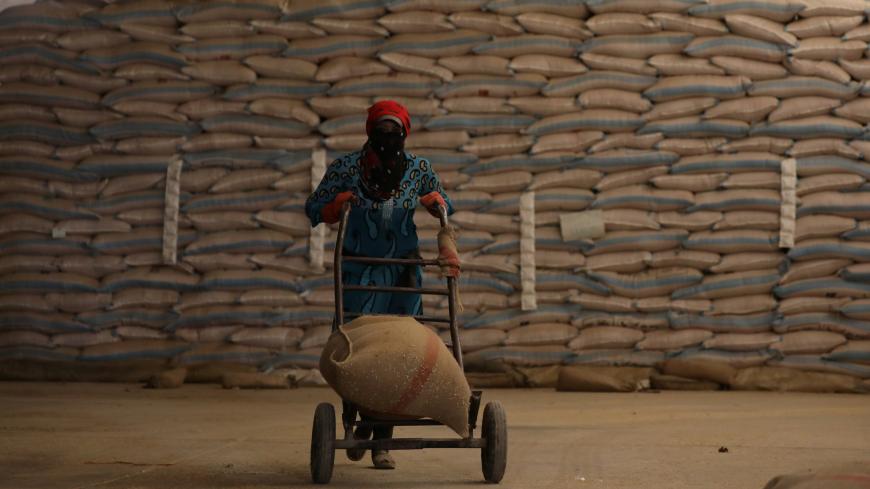 A woman pushes a cart loaded with a sack of wheat in Qamishli, Syria September 18, 2017. Picture taken September 18, 2017. REUTERS/Rodi Said  TO MATCH INSIGHT MIDEAST-CRISIS/SYRIA-WHEAT-ISLAMIC STATE - RC183B72BD10