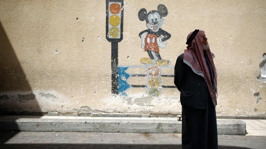 A Bedouin man stands next to a mural depicting Micky Mouse outside a polling station as Israelis vote in a parliamentary election, in the city of Rahat in Israel's southern Negev Desert April 9, 2019. REUTERS/Amir Cohen - RC175CC9E220