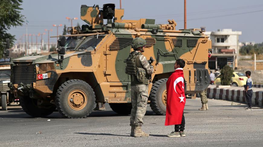 A boy wearing a Turkish flag stands next to a Turkish soldier in the town of Tal Abyad, Syria October 23, 2019. REUTERS/Khalil Ashawi     TPX IMAGES OF THE DAY - RC1FEACF7860