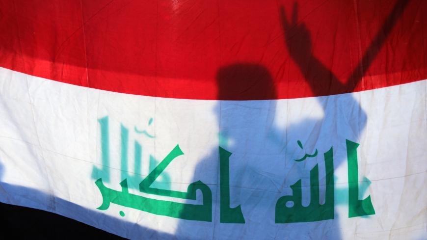 The shadow of an Iraqi demonstrator is seen on an Iraqi flag during ongoing anti-government protests in Kerbala, Iraq January 10, 2020. REUTERS/Abdullah Dhiaa al-Deen     TPX IMAGES OF THE DAY - RC22DE96XHT0