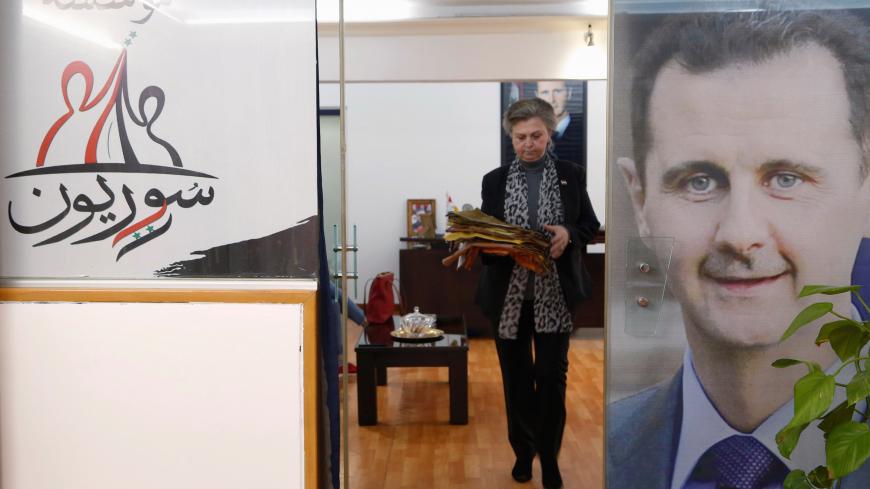 A Syrian parliamentarian and university student Janset Azan, 60, walks at her office decorated with a picture of Syria's President Bashar al-Assad in Damascus, Syria March 5, 2020. Picture taken March 5, 2020. REUTERS/Yamam Al Shaar - RC2TFF94HKUU
