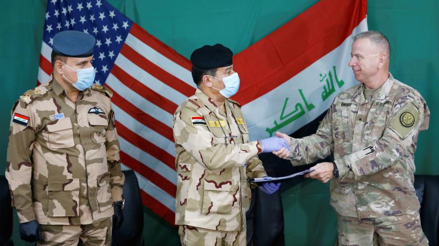 U.S. Brigadier General Vincent Barker shakes hands with Iraqi General Mohammed Fadel, as he wears face mask and gloves, following the outbreak of coronvavirus disease (COVID-19), during the hand over of Qayyarah Airfield West from US-led coalition forces to Iraqi Security Forces, in the south of Mosul, Iraq March 26, 2020. REUTERS/Thaier Al-Sudani - RC2SRF9VPYO2