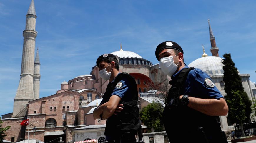 Turkish police officers wearing face masks, with the Byzantine-era monument of Hagia Sophia, now a museum, in the background, patrol at touristic Sultanahmet Square following the coronavirus disease (COVID-19) outbreak, in Istanbul, Turkey, June 5, 2020. REUTERS/Murad Sezer - RC213H9TTIHG