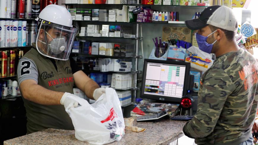 A man wears a protective face shield and a mask at a store during a curfew imposed to prevent the spread of the coronavirus disease (COVID-19), in Baghdad, Iraq June 7, 2020. REUTERS/Khalid al-Mousily - RC274H9RVUGM