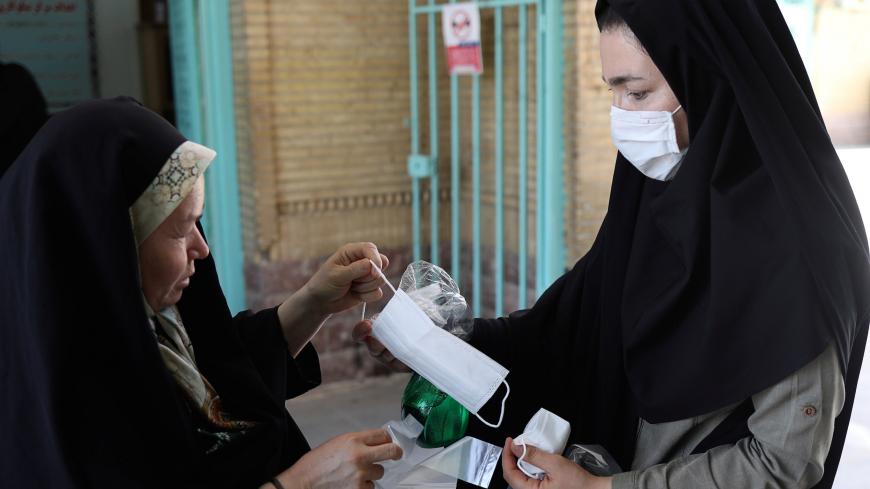 An Iranian woman gives a protective face mask to a worshipper to attend the Friday prayers in Qarchak Jamee Mosque, following the outbreak of the coronavirus disease (COVID-19), in Tehran province, in Qarchak, Iran, June 12, 2020. WANA (West Asia News Agency)/Ali Khara via REUTERS ATTENTION EDITORS - THIS PICTURE WAS PROVIDED BY A THIRD PARTY - RC2P7H9Y3JZH