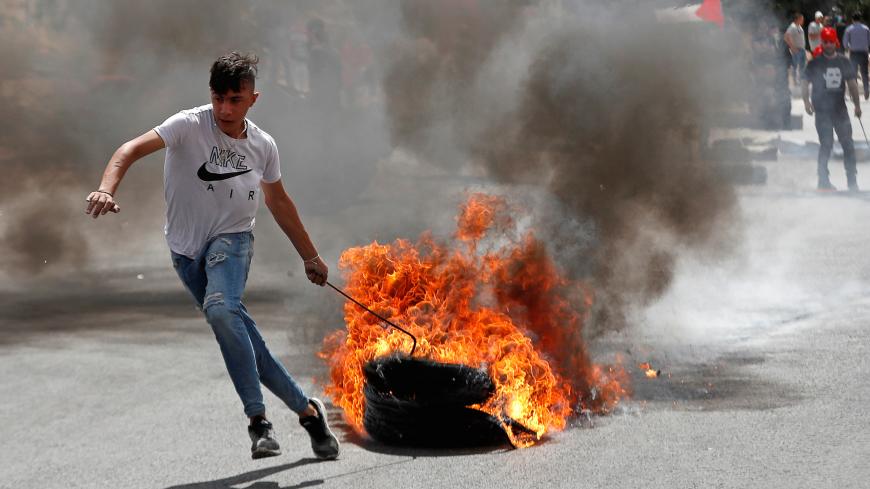 A Palestinian demonstrator pulls burning tires during a protest against Israel's plan to annex parts of the occupied West Bank, near the Jewish settlement of Beit El, near Ramallah June 19, 2020. REUTERS/Mohamad Torokman - RC2CCH92Y7IK