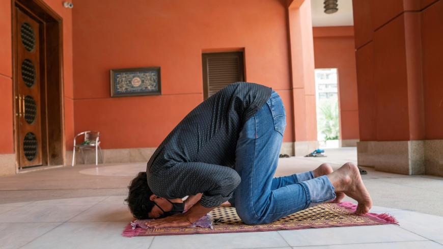 A man wearing a protective face mask prays on the first day of the holy month of Ramadan in the hallway of a mosque closed due to the outbreak of the coronavirus disease (COVID-19), in Kuwait City, Kuwait April 24, 2020. REUTERS/Stephanie McGehee - RC2ZAG9SCZVI