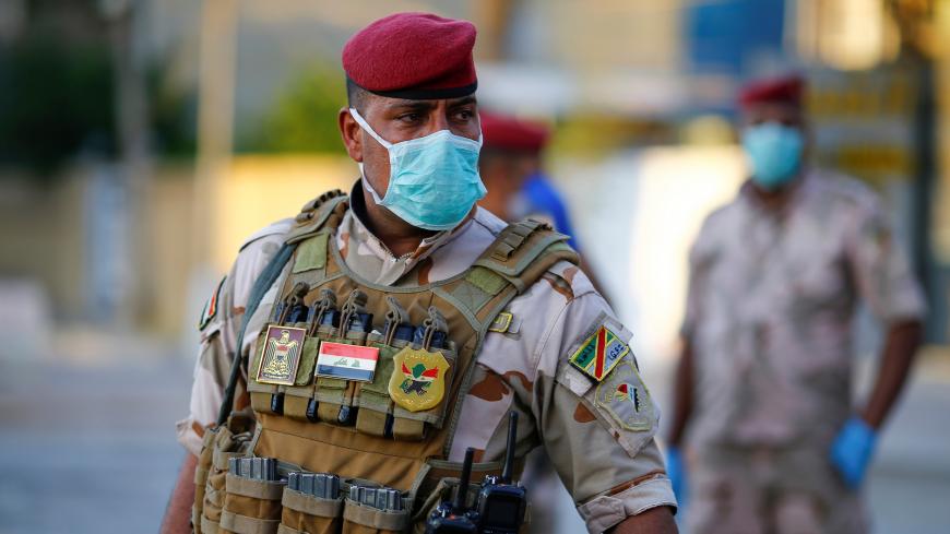 An Iraqi soldier wears a protective face mask as he stands guard at a check point, enforcing a curfew imposed to prevent the spread of the coronavirus disease (COVID-19), during the holy fasting month of Ramadan, in Baghdad, Iraq May 3, 2020.REUTERS/Thaier Al-Sudani - RC26HG9KD5MD