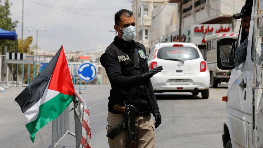 A member of Palestinian security forces gestures as he speaks with a truck occupant at a checkpoint after Palestinian President Mahmoud Abbas has extended to June 5 a state of emergency in response to the coronavirus crisis, in Hebron in the Israeli-occupied West Bank May 5, 2020. REUTERS/Mussa Qawasma - RC28IG9UZ9CC