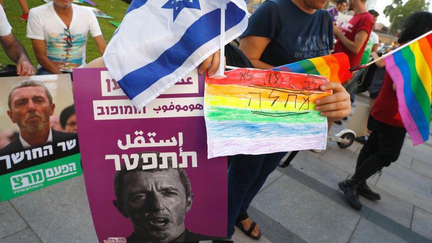 Members of the LGBT community hold a banner reading in Hebrew "A homophobic Racist Has to Quit" during a rally against Israel's Education Minister Rafi Peretz following his remarks on gay conversion therapy, in the Israeli coastal city of Tel Aviv on July 14, 2019. - Members of the LGBT community hold a banner reading in Hebrew "A homophobic Racist Has to Quiet" during a rally against Israel's Education Minister Rafi Peretz following his remarks on gay conversion therapy, in the Israeli coastal city of Tel 