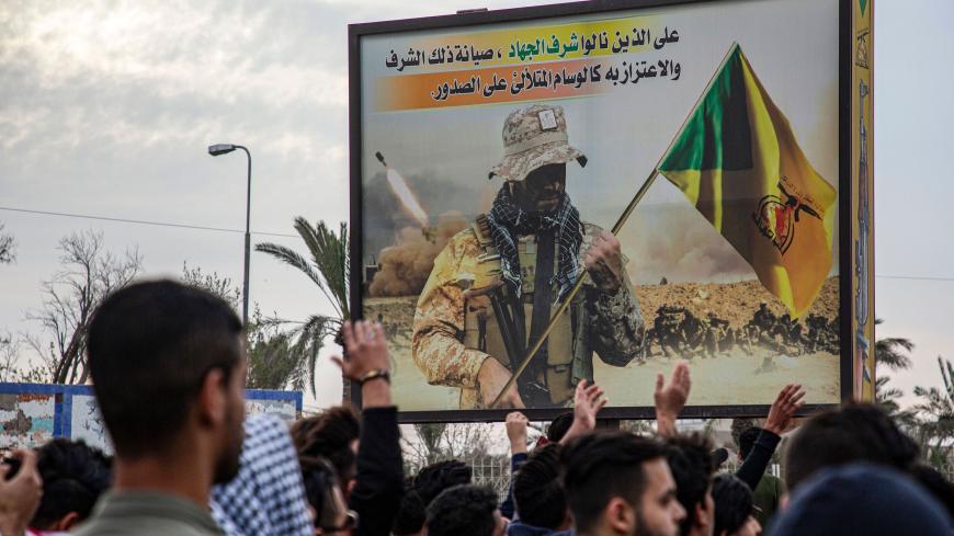 Protesters chant slogans as they walk past a pro-Hezbollah Brigades (militia that is part of the Hashed Shaabi or Popular Mobilisation Forces) billboard during an anti-government demonstration, also calling for freedom of the press, in the southern Iraqi city of Basra on January 17, 2020. (Photo by Hussein FALEH / AFP) (Photo by HUSSEIN FALEH/AFP via Getty Images)