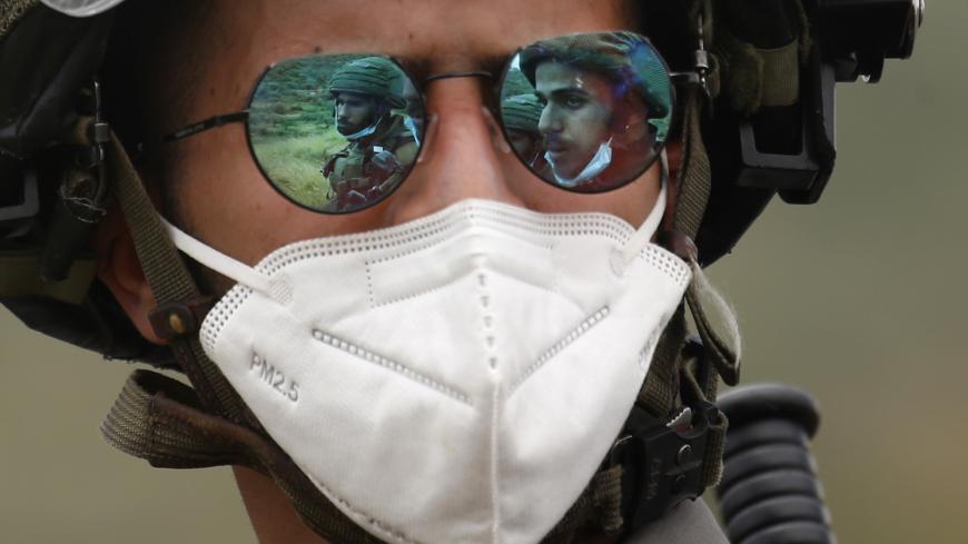 The images of two Israeli soldiers are projected on the sunglasses of a third one wearing a mask against the coronavirus Covid-19 during a protest by Palestinians against Israeli settlements on May 15, 2020 in al-Sawiya village, south of Nablus, in the occupied West Bank. (Photo by JAAFAR ASHTIYEH / AFP) (Photo by JAAFAR ASHTIYEH/AFP via Getty Images)