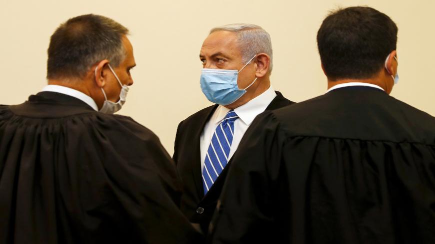 Israeli Prime Minister Benjamin Netanyahu (C), wearing a protective face maks, is pictured inside a courtroom at the district court of Jerusalem on May 24, 2020, during the first day of his corruption trial. - Fresh from forming a new government after more than 500 days of electoral deadlock, Netanyahu is expected to begin a new battle in the Jerusalem District Court -- to stay out of prison. The 70-year-old was scheduled to appear at a court hearing to formally confirm his identity to judges, after being i
