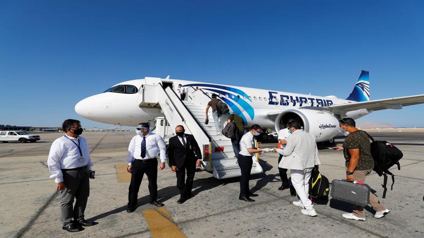 Mask-clad EgyptAir crew (safety measure due to the COVID-19 coronavirus pandemic) check the documents of travellers preparing to board an Airbus A320neo aircraft on the tarmac at Sharm el-Sheikh International Airport, in the Red Sea resort city at the southern tip of the Sinai peninsula on June 20, 2020. (Photo by Khaled DESOUKI / AFP) (Photo by KHALED DESOUKI/AFP via Getty Images)