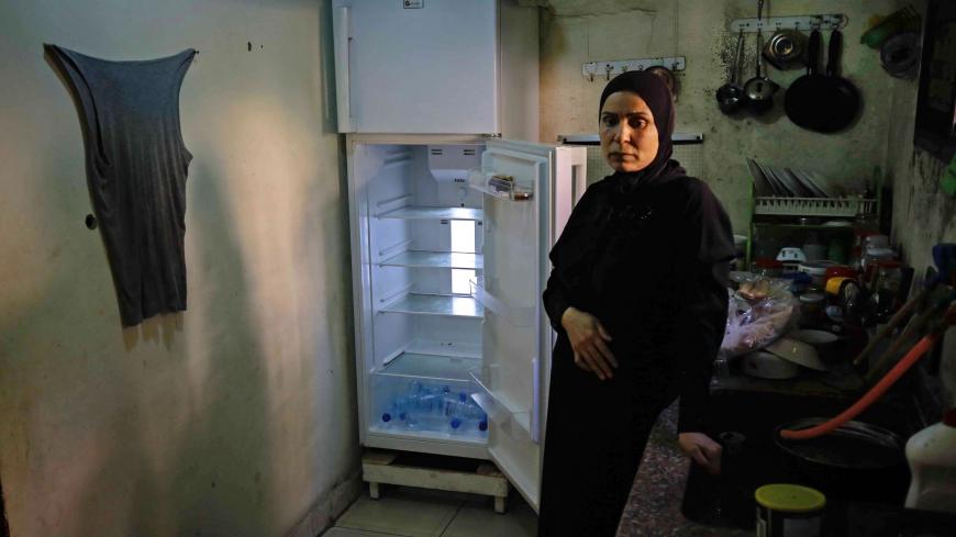 TOPSHOT - A Lebanese woman stands next to her empty refrigerator in her apartment in the port city of Tripoli north of Beirut on June 17, 2020. - Lebanon's economic crisis has led to a collapse of the local currency and purchasing power, plunging whole segments of the population into poverty as exemplified by near-empty fridges in many households. (Photo by IBRAHIM CHALHOUB / AFP) (Photo by IBRAHIM CHALHOUB/AFP via Getty Images)