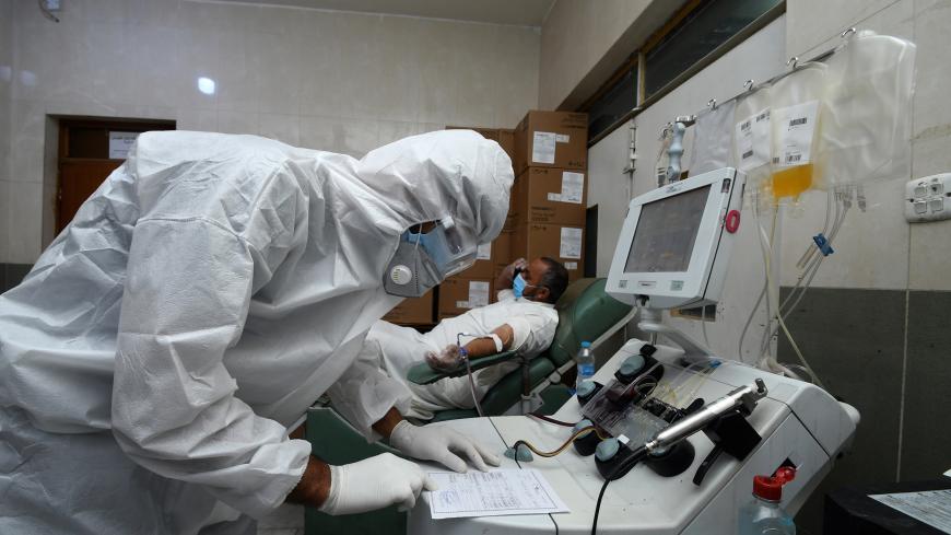 An Iraqi phlebotomist draws blood plasma from a recovered COVID-19 patient at the blood bank of Iraq's southern city of Nasiriyah in Dhi Qar province, on June 24, 2020. (Photo by Asaad NIAZI / AFP) (Photo by ASAAD NIAZI/AFP via Getty Images)