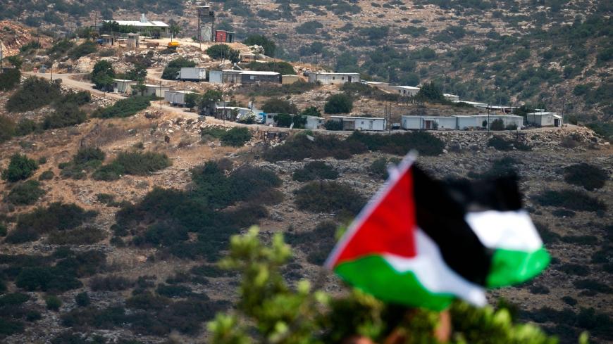 Palestinian demonstrators wave national flags during a protest against the expansion of existing Jewish settlements, in the town of Biddya, in the Israeli-occupied West Bank on July 6, 2020. In the background bungalows built by settlers on the outskirts of the Karni Shamron settlement are visible. (Photo by JAAFAR ASHTIYEH / AFP) (Photo by JAAFAR ASHTIYEH/AFP via Getty Images)