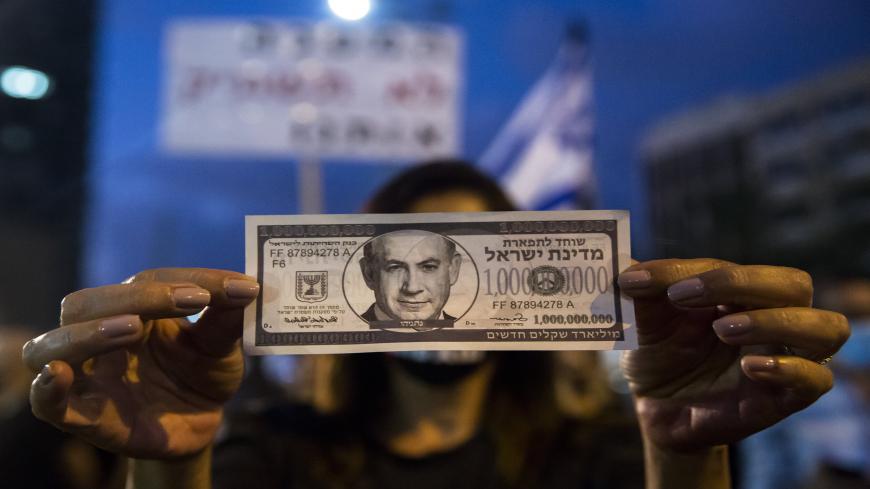 TEL AVIV, ISRAEL - JULY 11:  Israeli Protester holds a fake bill with  a photo of the Israeli Prime Minister Benjamin Netanyahu as she protests against the Government's economy response to the cororna virus crisis on July 11, 2020 in Tel Aviv, Israel. Following a rise in the cases of COVID-19, Israeli Prime Minister Benjamin Netanyahu has ordered many businesses to shut, causing people to protest about a perceived mishandling of the coronavirus pandemic and to call for the compensation promised by the gover