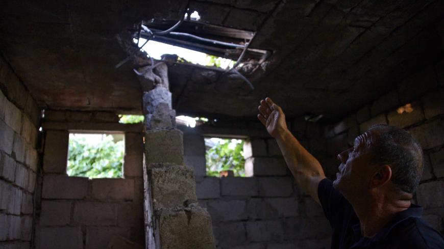 Hrachik Pogosyan, 55, points at the roof of his house in the village of Aygepar in Tavush region damaged by recent shelling during armed clashes on the Armenian-Azerbaijani border on July 15, 2020. - Defence officials in Armenia and Azerbaijan said fighting on their border subsided on July 15, 2020 after several days of deadly clashes raised fears of a major flare-up. At least 16 people on both sides were killed in three days of shelling that started Sunday between the ex-Soviet republics, which have been l