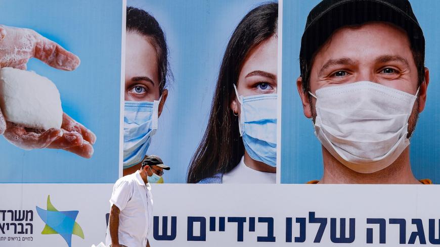 A mask-clad man walks past a billboard showing other mask-clad faces and adequate social distance measures, raising awareness about COVID-19 coronavirus pandemic precautions, in the centre of the Israeli city of Ramat Gan, east of Tel Aviv, on July 17, 2020. - Israel's government said it was imposing new restrictions to limit the spiraling spread of coronavirus in the hope of avoiding a general lockdown further along the line. It said that from 5:00pm local time (1400 GMT) on Friday until 5:00am every Sunda