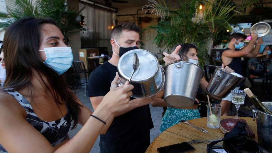 Mask-clad Israeli restaurant owners and clients protest against new lockdown measures imposed by the authorities due to a surge in coronavirus cases,  by banging ice buckets, in the Israeli coastal city of Tel Aviv, on July 17, 2020. - Israel's government said today it was imposing new restrictions to limit the spiralling spread of coronavirus in the hope of avoiding a general lockdown further along the line. (Photo by JACK GUEZ / AFP) (Photo by JACK GUEZ/AFP via Getty Images)