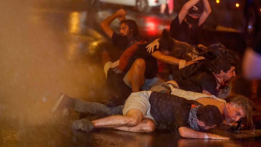 TOPSHOT - Protesters crouch down as Israeli police use water cannons during clashes at a demonstration against the Israeli prime minister outside his official residence in Jerusalem, early on July 22, 2020. - Israeli Prime Minister Benjamin Netanyahu, 70, was indicted in January for bribery, fraud and breach of trust in three cases. He denies all the charges and accuses the media and legal officials of a witch hunt. (Photo by AHMAD GHARABLI / AFP) (Photo by AHMAD GHARABLI/AFP via Getty Images)