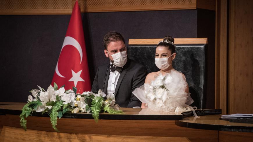 ISTANBUL, TURKEY - JULY 01: Groom Okan Barut and bride Oya Kulaksiz wear face masks as they take part in their wedding ceremony at the Kadikoy Municipality marriage office on July 01, 2020 in Istanbul, Turkey. Restrictions on Turkish wedding halls were lifted on July 01, 2020 after being closed for months due to the Coronavirus pandemic. Turkey continues to slowly ease restrictions after recently reopening, cafes, restaurants, parks and inter-city travel.  (Photo by Chris McGrath/Getty Images)