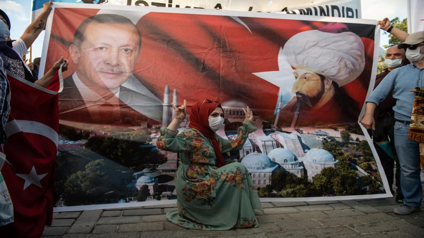 ISTANBUL, TURKEY - JULY 10: A woman gestures infront of a placard depicting Turkish President Tayyip Erdogan and Ottoman Sultan Mehmet II, also known as Mehmet the Conqueror, outside Istanbul's famous Hagia Sophia on July 10, 2020 in Istanbul, Turkey. Turkey's top administrative court ruled to annul a 1934 decree that turned the historic Hagia Sophia into a museum. The controversial ruling opens the way for the structure to be converted back into a mosque after 85 years. President Recep Tayyip Erdoğan hande