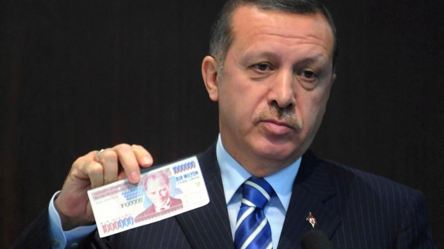 Turkish Prime Minister Tayyip Erdogan displays an banknote of the old Turkish Lira at a news conference in Ankara October 3, 2008. Turkey will return to its old currency, the Turkish Lira, on January 1, after a major money reform four years ago that saw the introduction of the New Turkish Lira. The banner in the background reads "The Turkish lira is coming". AFP PHOTO/ADEM ALTAN (Photo credit should read ADEM ALTAN/AFP via Getty Images)