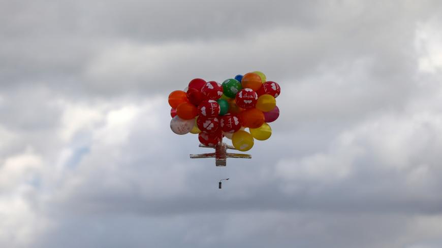 Balloons carrying an incendiary device floats after being released by masked Palestinians near Gaza's Bureij refugee camp, along the Israel-Gaza border fence, on February 10, 2020. (Photo by MAHMUD HAMS / AFP) (Photo by MAHMUD HAMS/AFP via Getty Images)